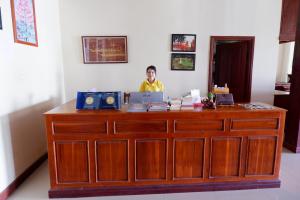 a man standing behind a desk in a room at Kongmany Prestige Hotel in Muang Không