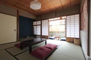 een woonkamer met een tafel en een aantal ramen bij Hashibaya TABI-NE in Kanazawa