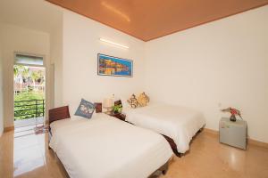 - 2 lits dans une chambre aux murs blancs dans l'établissement Strawberry Garden Homestay, à Hội An
