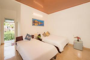 two beds in a room with white walls at Strawberry Garden Homestay in Hoi An