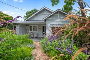 a white house with a brick walkway in the garden at Kurrajong Holiday House - Family in Kurrajong