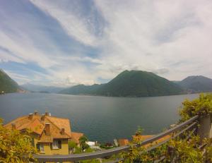 a view of a lake with a house and mountains at Studio Apartment Open Space with Terrace in Argegno +1 photo