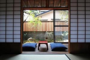 a door to a room with a table and blue pillows at Hashibaya TABI-NE in Kanazawa