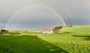 un arco iris sobre un campo verde con una casa en Maison de pêcheur vue mer exceptionnelle, en Audinghen