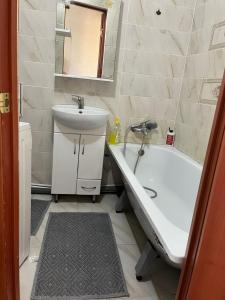 ein Badezimmer mit einem Waschbecken, einer Badewanne und einem Waschbecken in der Unterkunft Квартира с изолированными комнатами in Oral
