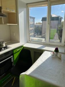 eine Küche mit einem Tisch und einem großen Fenster in der Unterkunft Квартира с изолированными комнатами in Oral