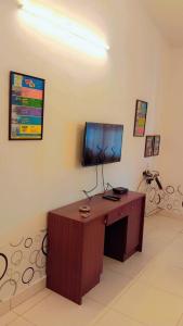 una camera con scrivania e TV appesa a un muro di Ronne's Beachway 2BHK Apartment a Calangute