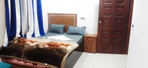 a bedroom with a bed with blue pillows and a door at Hilsan Hotel in Bomdila