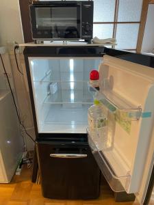 an empty refrigerator with its door open in a kitchen at 萩ゲストハウスラビット in Hagi