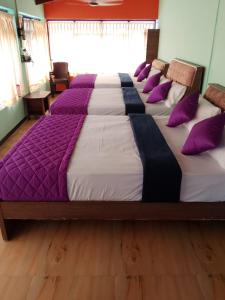 uma cama grande com almofadas roxas e brancas em SD Residency - Yercaud em Yercaud
