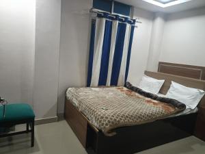 a small bedroom with a bed with a blue curtain at Hilsan Hotel in Bomdila
