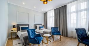 a hotel room with two beds and blue chairs at Hotel Pavco in Gorzów Wielkopolski
