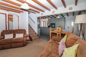 a living room with two couches and a kitchen at Acorn Cottage in Newton Abbot
