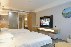 a hotel room with two beds and a flat screen tv at Paco Hotel Guangzhou North Railway Station in Huadu