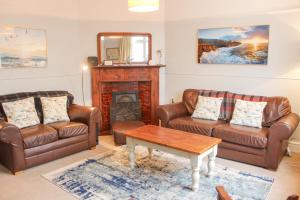 a living room with leather furniture and a fireplace at Waders in Salcombe