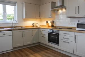 a kitchen with white cabinets and a stove top oven at Waders in Salcombe