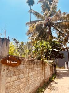 un cartel en una pared de ladrillo con una palmera en The Window, en Matara