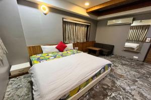 a bedroom with a large bed with a red pillow at Hotel Om Balaji in Ahmedabad