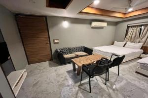 Hotel Om Balaji في أحمد آباد: غرفة بسرير وطاولة وأريكة