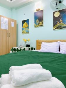 a bedroom with a green bed with towels on it at Bao Long Guest House in Cat Ba