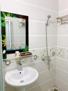 a white bathroom with a sink and a mirror at Long Guest House in Cat Ba