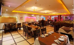 een restaurant met tafels en stoelen en een man in een kamer bij LA SAPPHIRE HOTEL & RESTUARANT in New Delhi