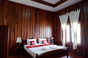 a bedroom with a bed with wooden walls and a window at Kongmany Prestige Hotel in Muang Không