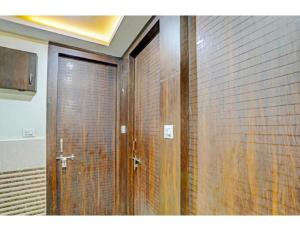 a bathroom with a wooden door next to a brick wall at Hotel Avenue, Kanpur in Kānpur