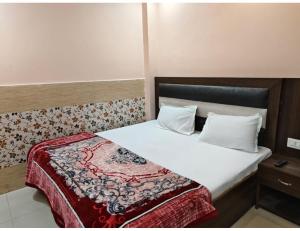 a bedroom with a bed with a red blanket on it at Hotel Avenue, Kanpur in Kānpur