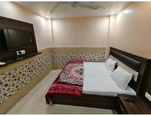 a small bedroom with a bed and a tv at Hotel Avenue, Kanpur in Kānpur