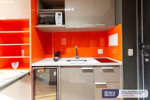een oranje keuken met een wastafel en een magnetron bij MH 50202 - Maravilhoso Studio Expo Center AC/WF/VG in Sao Paulo