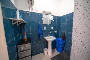 a blue tiled bathroom with a sink and a toilet at Charmant Studio bien équipé in Dakar