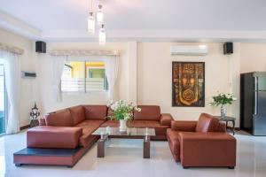 una sala de estar con sofás de cuero marrón y una mesa. en Family 3BR Villa Platinum, Private Pool, Gated Residence, in middle of Naiharn and Rawai Beach, en Rawai Beach