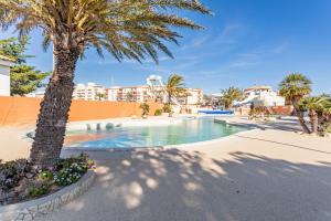 a swimming pool with palm trees and buildings at Mobilhome Soleia 2023 Mar Estan 4x in Canet-en-Roussillon