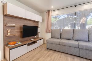 a living room with a couch and a flat screen tv at Mobilhome Soleia 2023 Mar Estan 4x in Canet-en-Roussillon