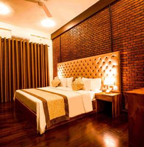 um quarto com uma cama grande e uma parede de tijolos em Manthra Leisure em Kandy