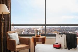 a hotel room with a bed and a chair and a window at Millennium Hotel London Knightsbridge in London +33 photos