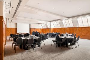 una sala de conferencias con mesas y sillas y una pantalla de proyección en Millennium Hotel London Knightsbridge en Londres