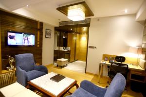 uma sala de estar com cadeiras azuis e uma televisão em Regenta Central the Crystal Kanpur, em Kanpur