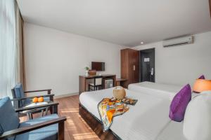 um quarto de hotel com uma cama e uma cadeira em Bantique Hotel em Da Nang