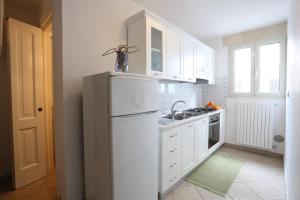 a kitchen with white cabinets and a white refrigerator at Appartamento Sant'Antonio in Castro di Lecce