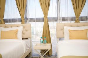 2 camas en una habitación con cortinas y mesa auxiliar en Z Bliss Suites, BKC, en Bombay