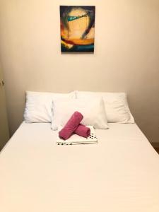 a white bed with a pair of pink shoes on it at Casi Cozy Spacious Condo For Family, Free Wifi, Netlfix and Pool in Davao City