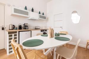 a white kitchen with a white table and chairs at Cosy T2 Charme confort - Cœur de Lille Sebastopol by Lity in Lille