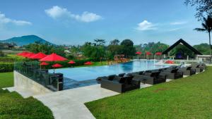 uma piscina com cadeiras e guarda-sóis vermelhos em ASTON Serang Hotel & Convention Center em Serang