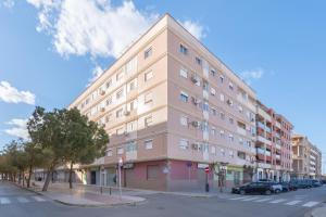 een groot roze gebouw met auto's geparkeerd voor het bij Ca Vivi in Catarroja