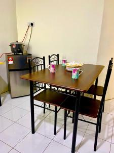 Suhana LongHouse HomeStay Sipitang في Sipitang: طاولة خشبية مع كرسيين وطاولة مع أكواب