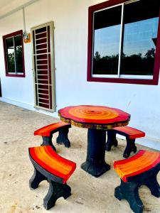 Suhana LongHouse HomeStay Sipitang في Sipitang: طاولة و كرسيين امام المبنى