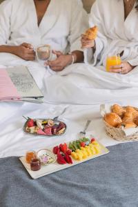 two people sitting in bed with breakfast foods and drinks at ZUR Studios and Suites in Beirut
