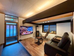 ein Wohnzimmer mit einem Sofa und einem Flachbild-TV in der Unterkunft YudaOnsen Byakkoan　山口湯田温泉 白狐庵 in Yamaguchi